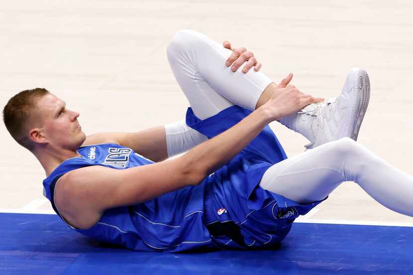 Dallas Mavericks center Kristaps Porzingis (6) grabs his ankle after falling to floor under...