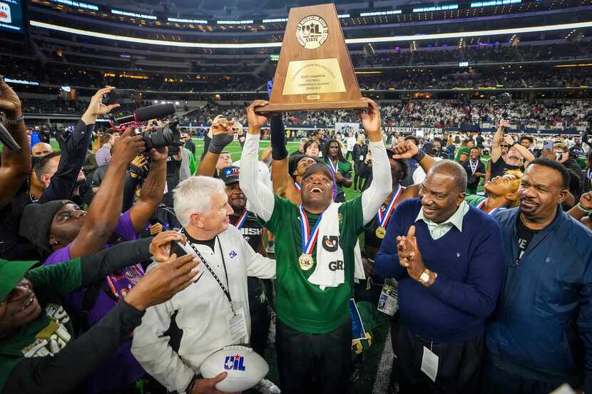 DeSoto football coach Claude Mathis lifts the championship trophy after a victory over...