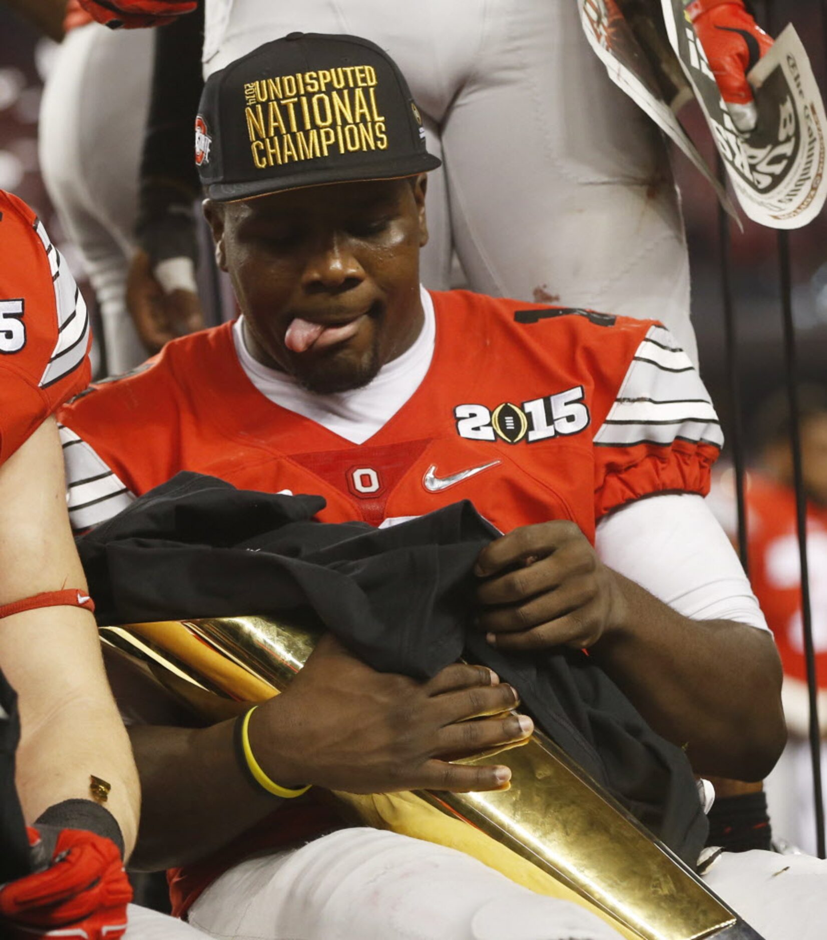 Ohio State Buckeyes quarterback Cardale Jones (12) covers the National Championship Trophy...