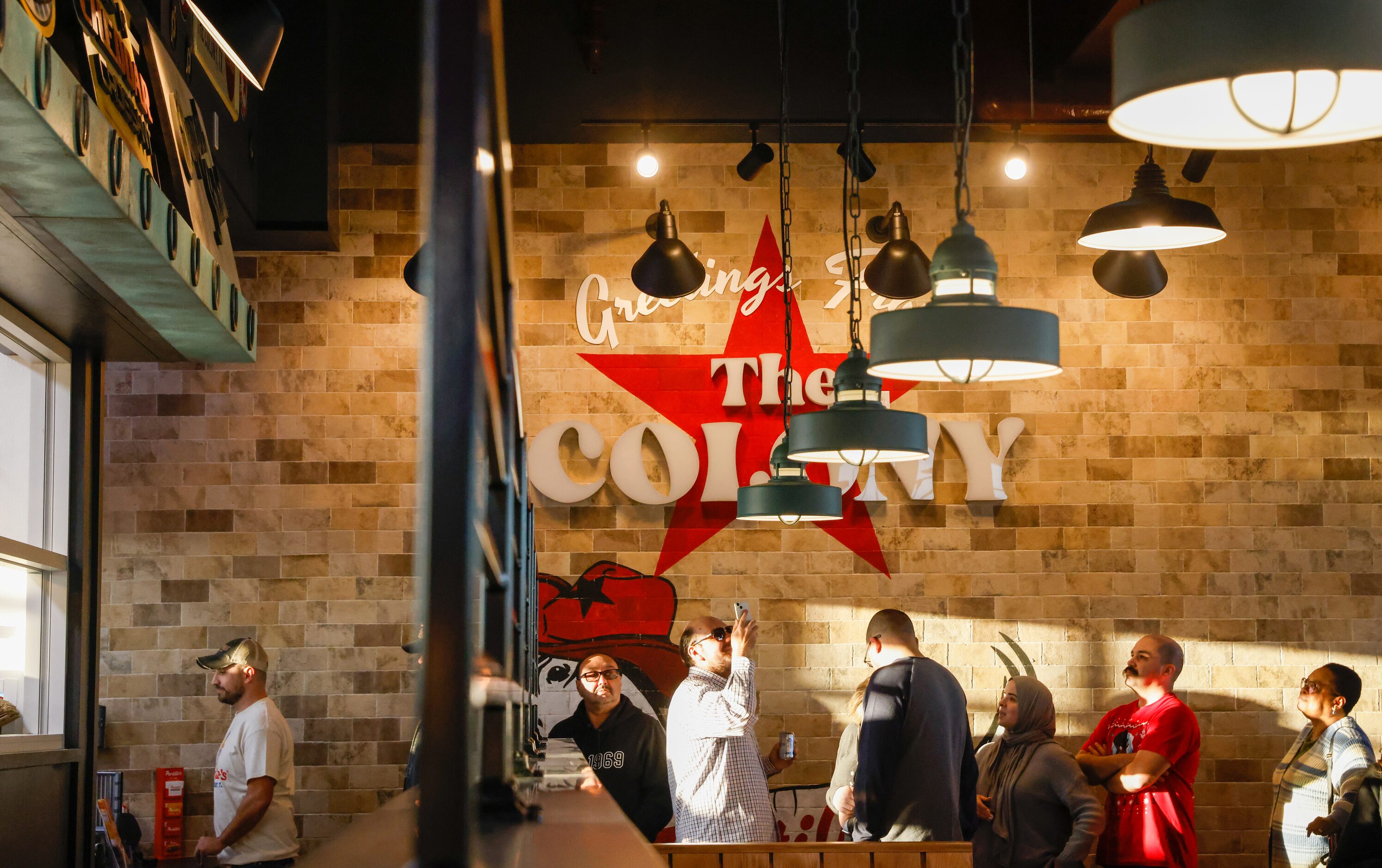 The first guests in the new Portillo’s in The Colony take pictures and look up at the menu...