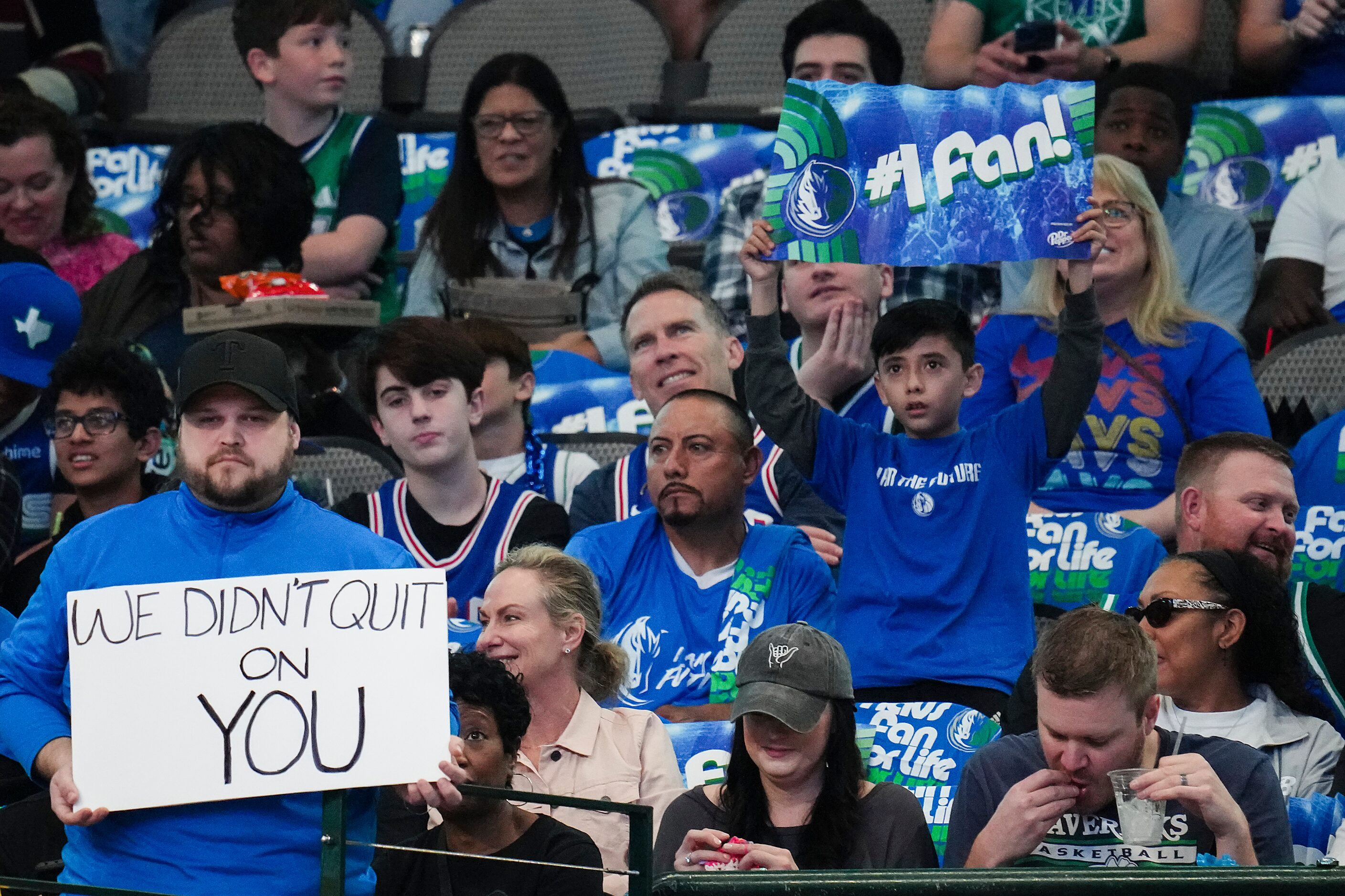 On fan appreciation day, a Dallas Mavericks fan holds a sign reading “We Didn’t Quit on You”...