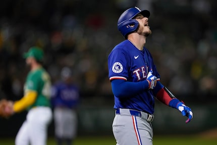 Texas Rangers' Jonah Heim, right, reacts after being hit by a pitch with the bases loaded...