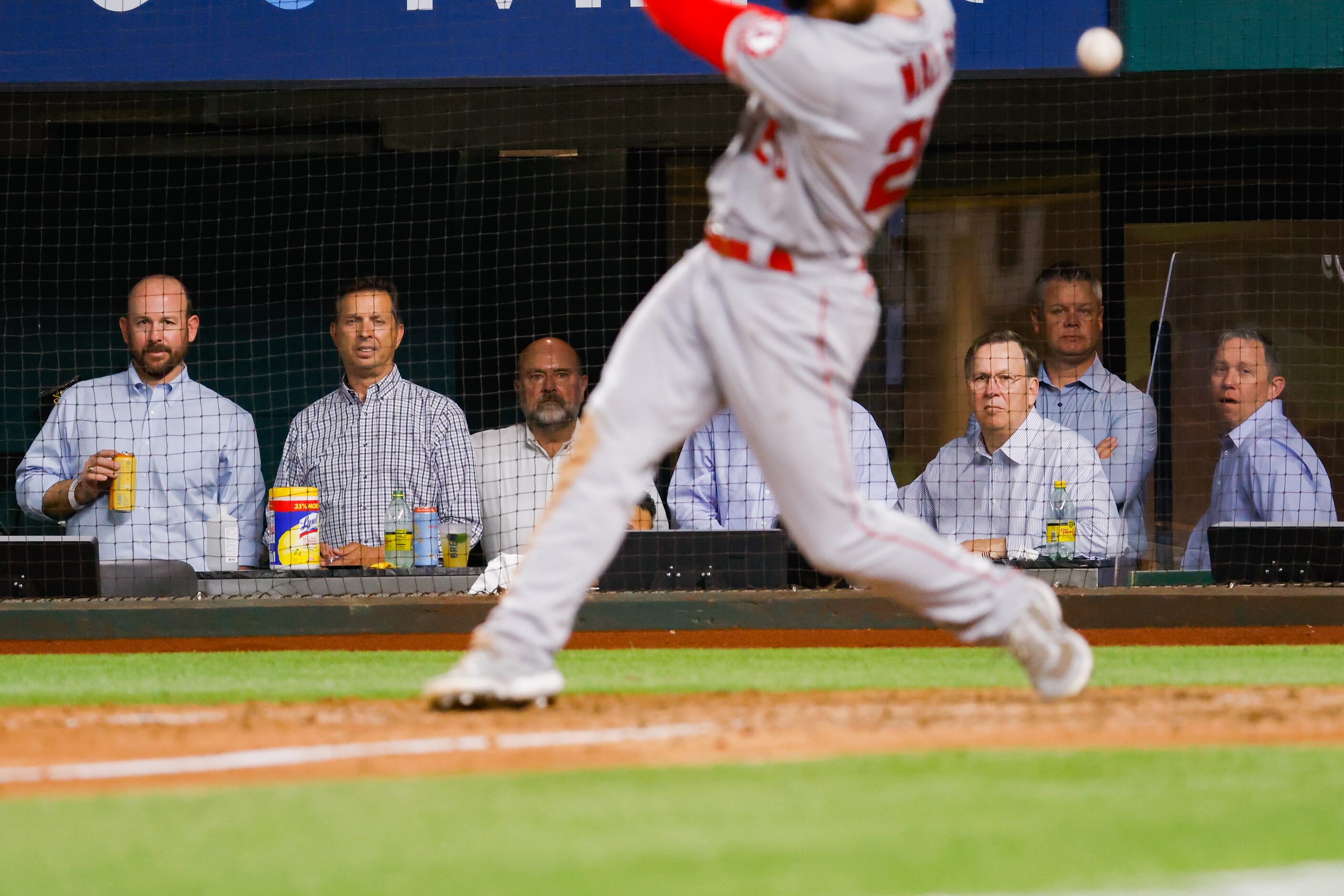 Men in business casual attire watch the eighth inning of an MLB game between the Texas...