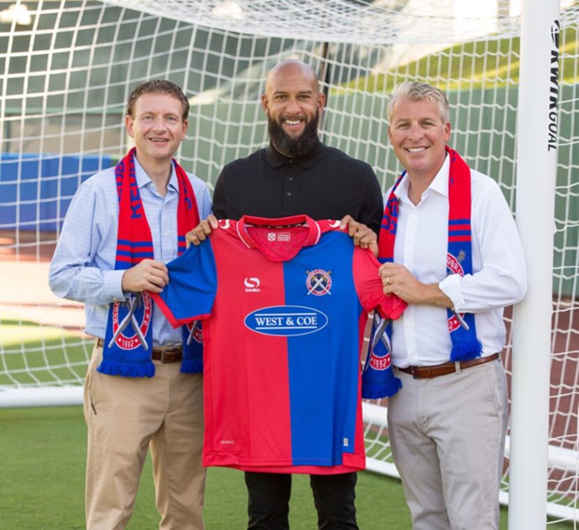 Former US Men's National Team goalkeeper Tim Howard (center) holds a Dagenham & Redbridge...