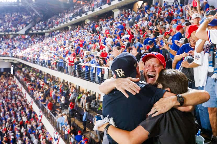 Texas Rangers fans Brian Crowley (center) hugs Liam Crowley, (right), and Nick Wilhelmson...