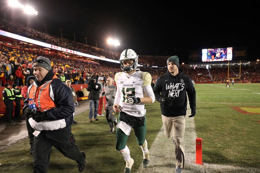 Baylor quarterback Charlie Brewer, center, is escorted off the field after he was ejected...