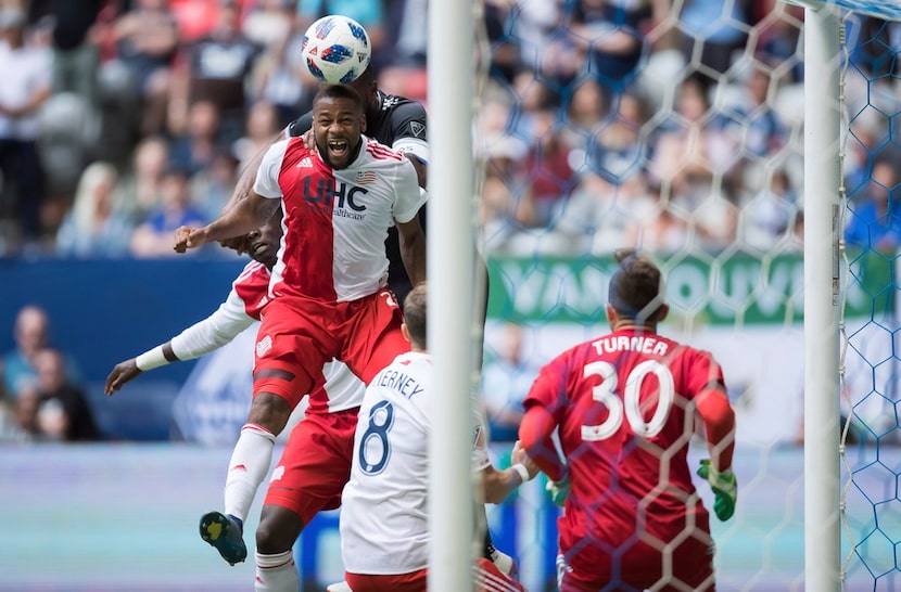 New England Revolution's Andrew Farrell, front left, gets his head on the ball while...