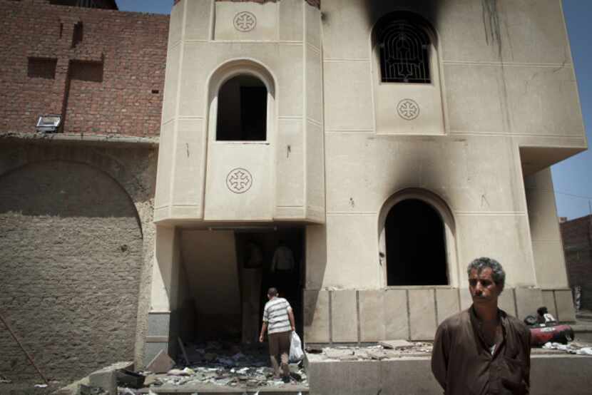 Coptic Christians walk outside of a burned church building near the destroyed New Church of...