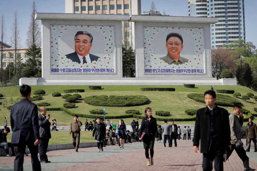 North Koreans walk along downtown Pyongyang where portraits of the late leaders, Kim Il...