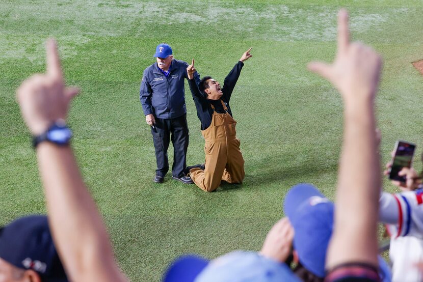 Security detains a fan who ran onto the field following Texas Rangers winning the World...