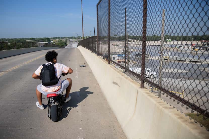 A Joppa resident on a motorbike looks toward the Austin Bridge & Road South Dallas Plant...