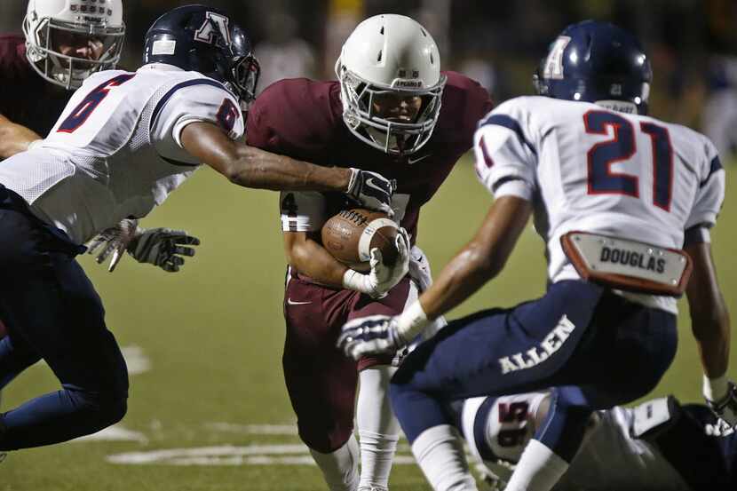 Plano running back Lopaka Yoro (14) is met by Allen defensive backs Anthony Taylor (6) and...