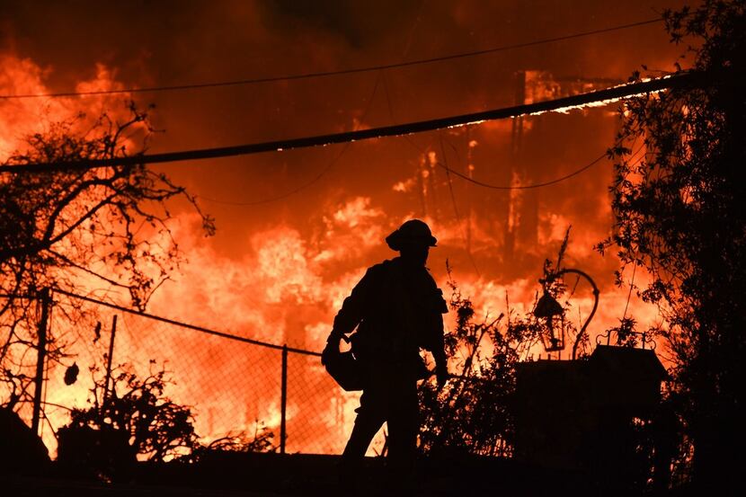 A firefighter is silhouetted by a burning home along Pacific Coast Highway (Highway 1)...