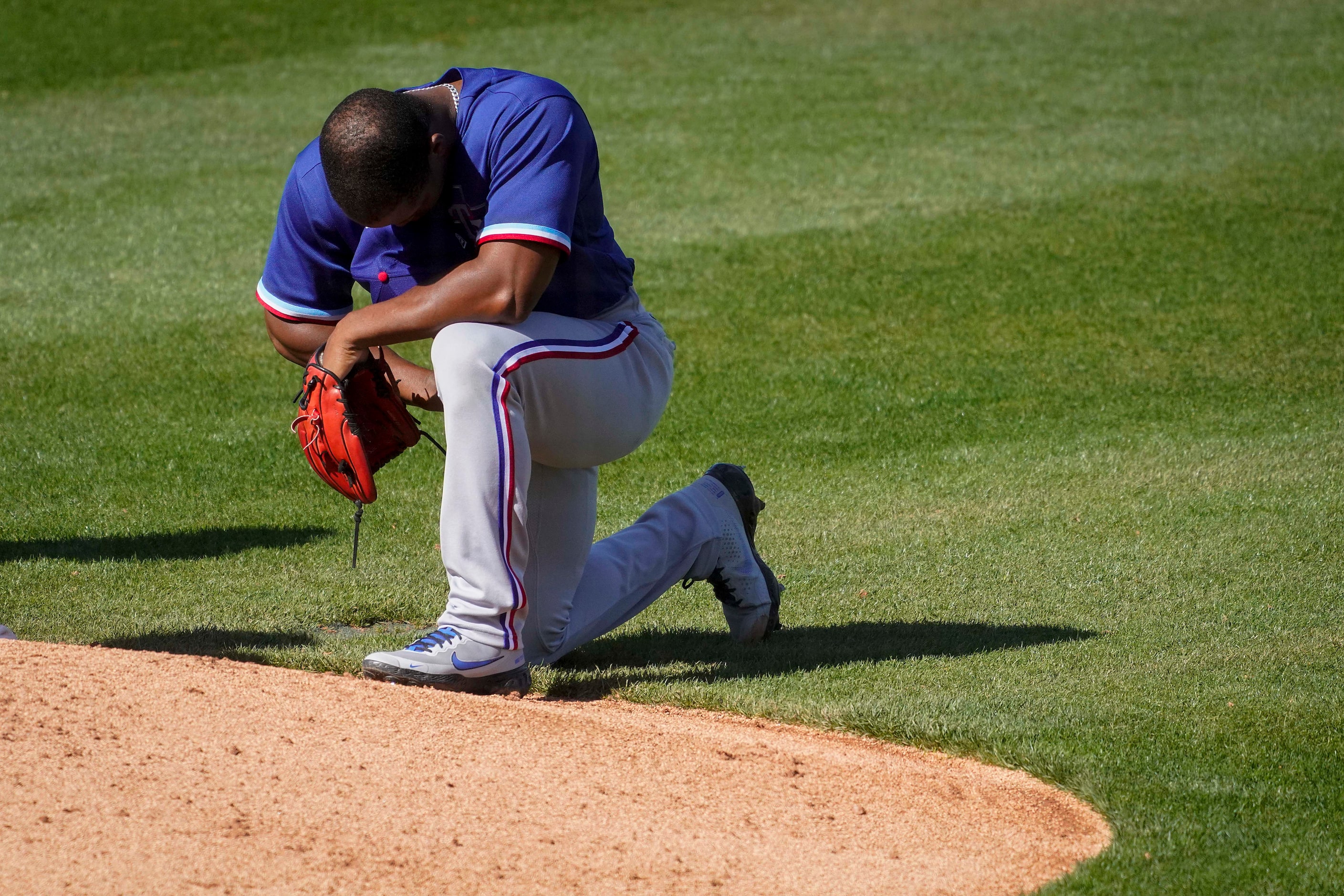 Texas Rangers pitcher Fernery Ozuna takes a knee before pitching during the sixth inning of...