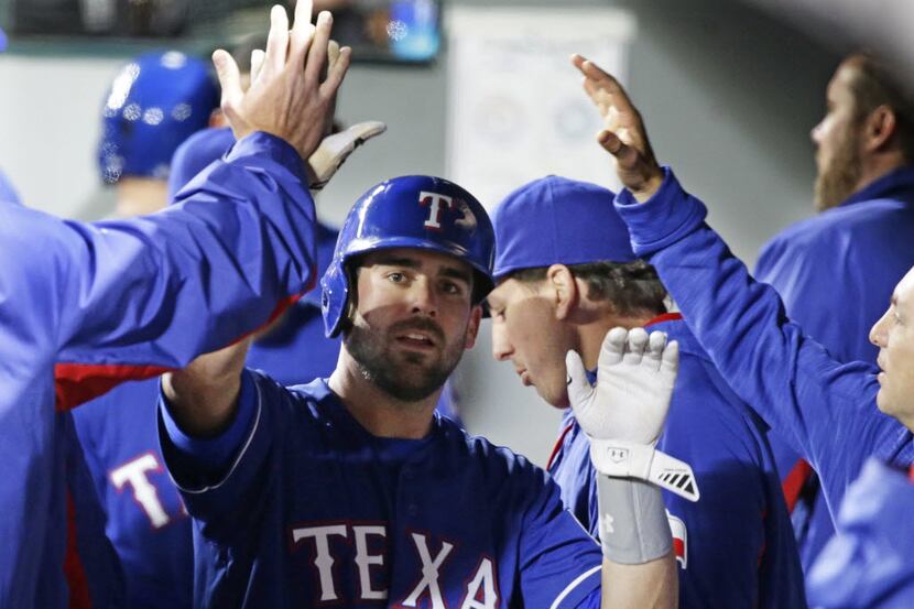 Texas Rangers' Brett Nicholas is greeted in the dugout after he scored a run in the seventh...