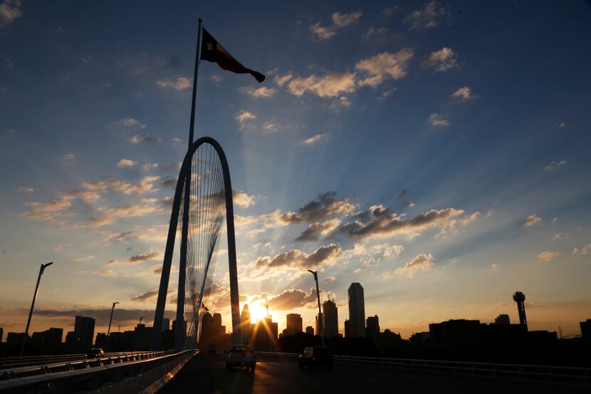 The sun emerges over the Dallas skyline with the Margaret Hunt Hill Bridge  in the...