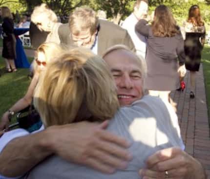  Governor Greg Abbott hugs fellow high school classmate Michelle Gerke Parker during the...