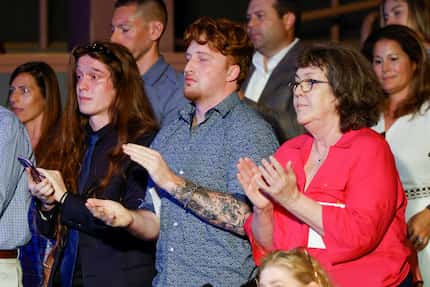 Tyson Fraley (left) and Sam Fraley (center) stand and applaud alongside their mother Pam...