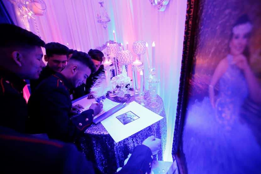 Members of the Latin Boyz Cadets sign the quinceañera's guest book.