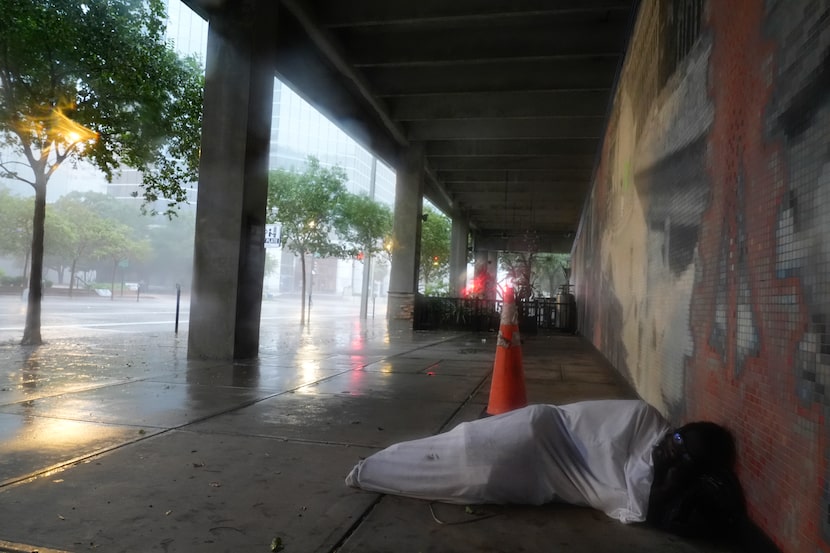 Melvin Lee Hicks, who is homeless, lies under a sheet donated by a nearby hotel, as he...