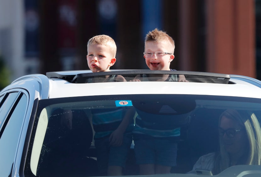 Parked with social distancing in mind, two young boys watch a concert outside of Globe Life...