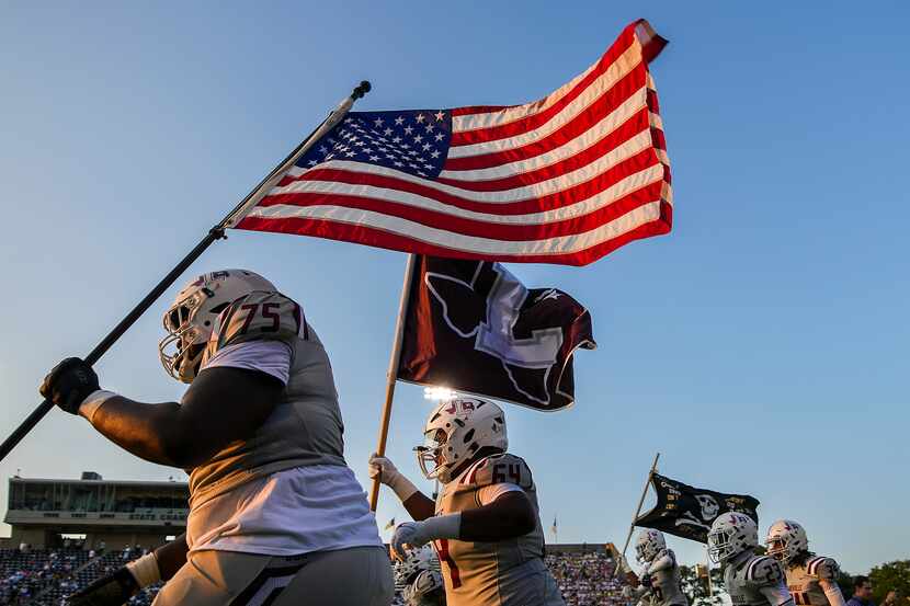 Lewisville offensive lineman Xavion Davis (75) carries the American flag as the team takes...