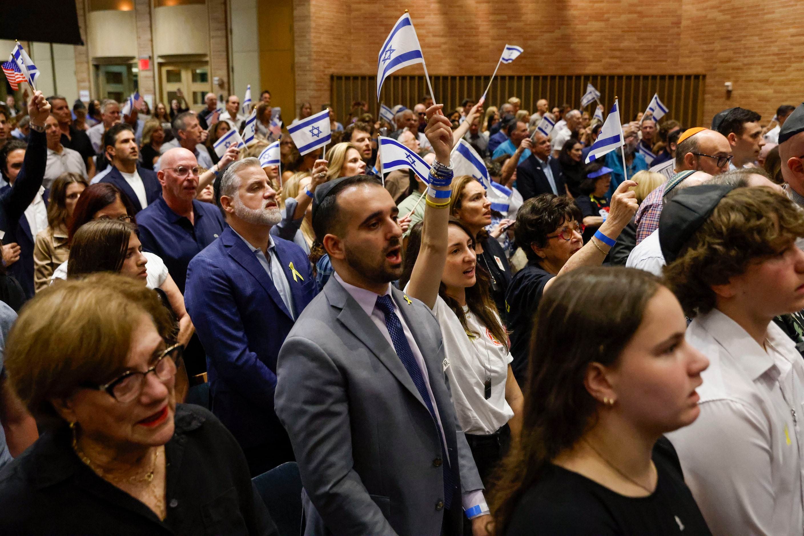 People stand and sing the Israeli national anthem during a community event commemorating the...