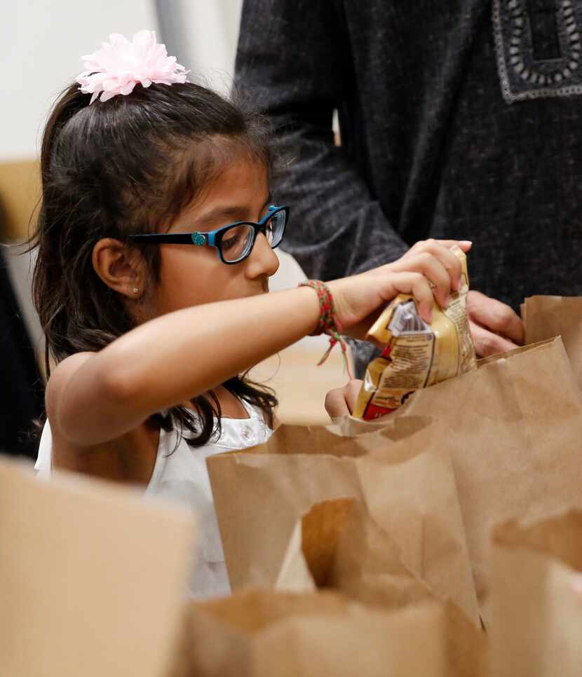 Samaira Verani, 5, packs a snack bag to be donated to various area food pantries at Ismaili...