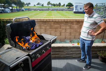 Warner Cutbill burns a Dallas Cowboys jersey on the grill in his backyard, which backs up to...