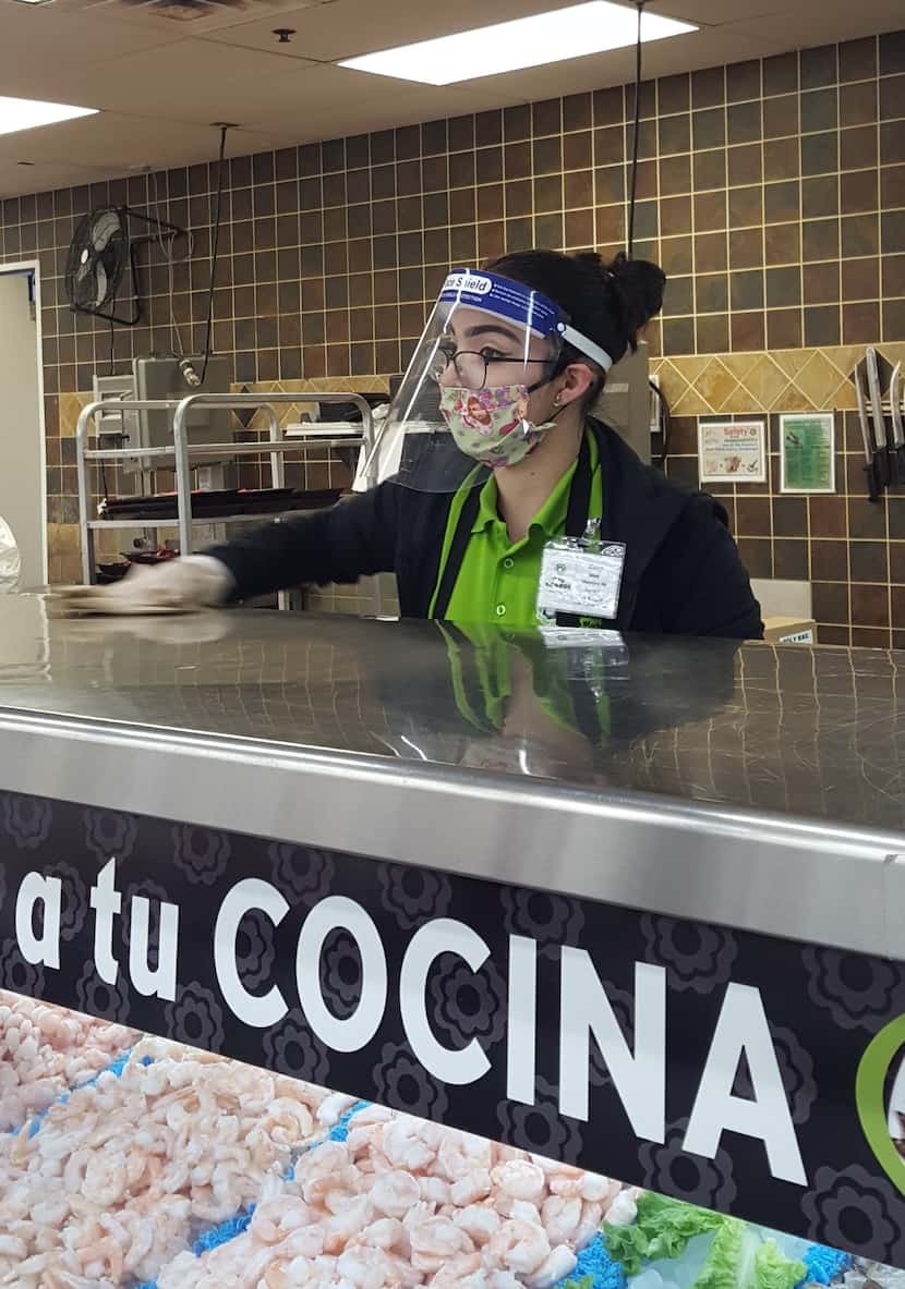 Trabajadores de El Río Market Latin Market portan protectores faciales plásticos para...