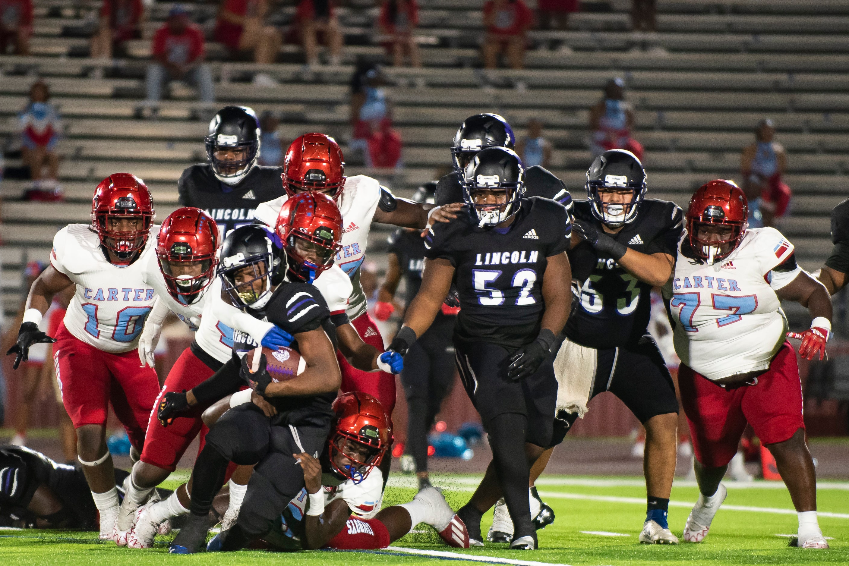 Lincoln senior Jaquan Smith (5) is brought down by Carter defenders after gaining yardage...