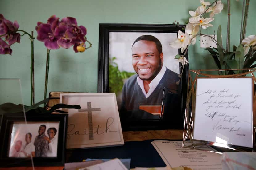 A large photo of Botham Jean with photos and cards is displayed on one of the tables in his...