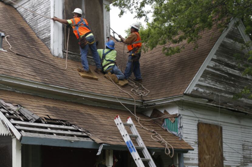 Workers from Johnson Roofing helped board up windows in a home across the field from the...