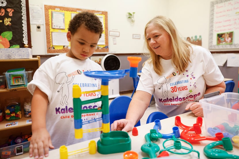 Robert Hart (left) watches as owner and director Diana Mizell helps him with his marble run...