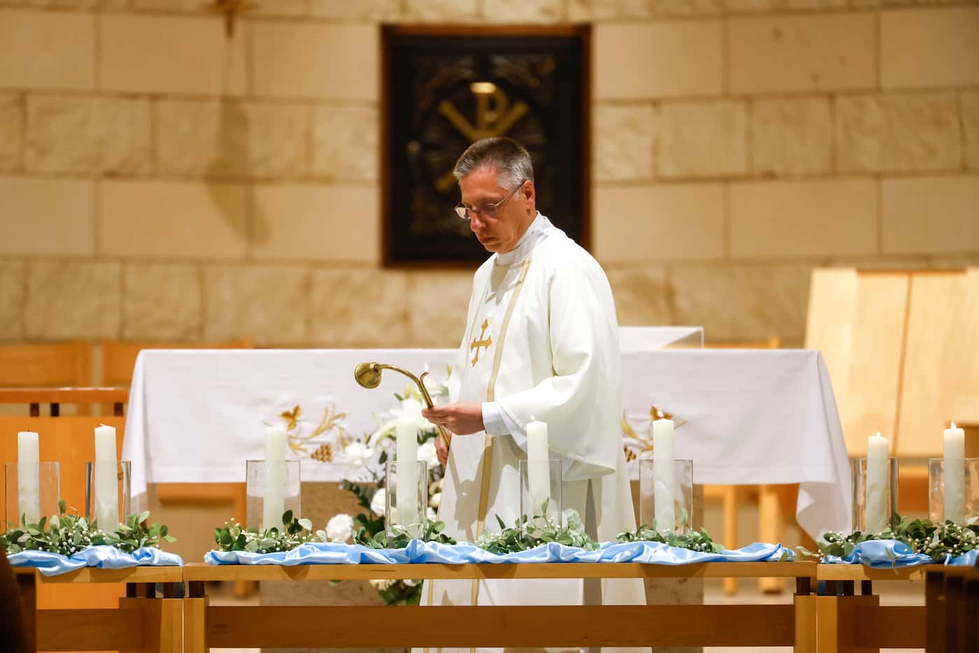 Deacon Ken Steponaitis lights the candles during a vigil and community mass on Wednesday,...
