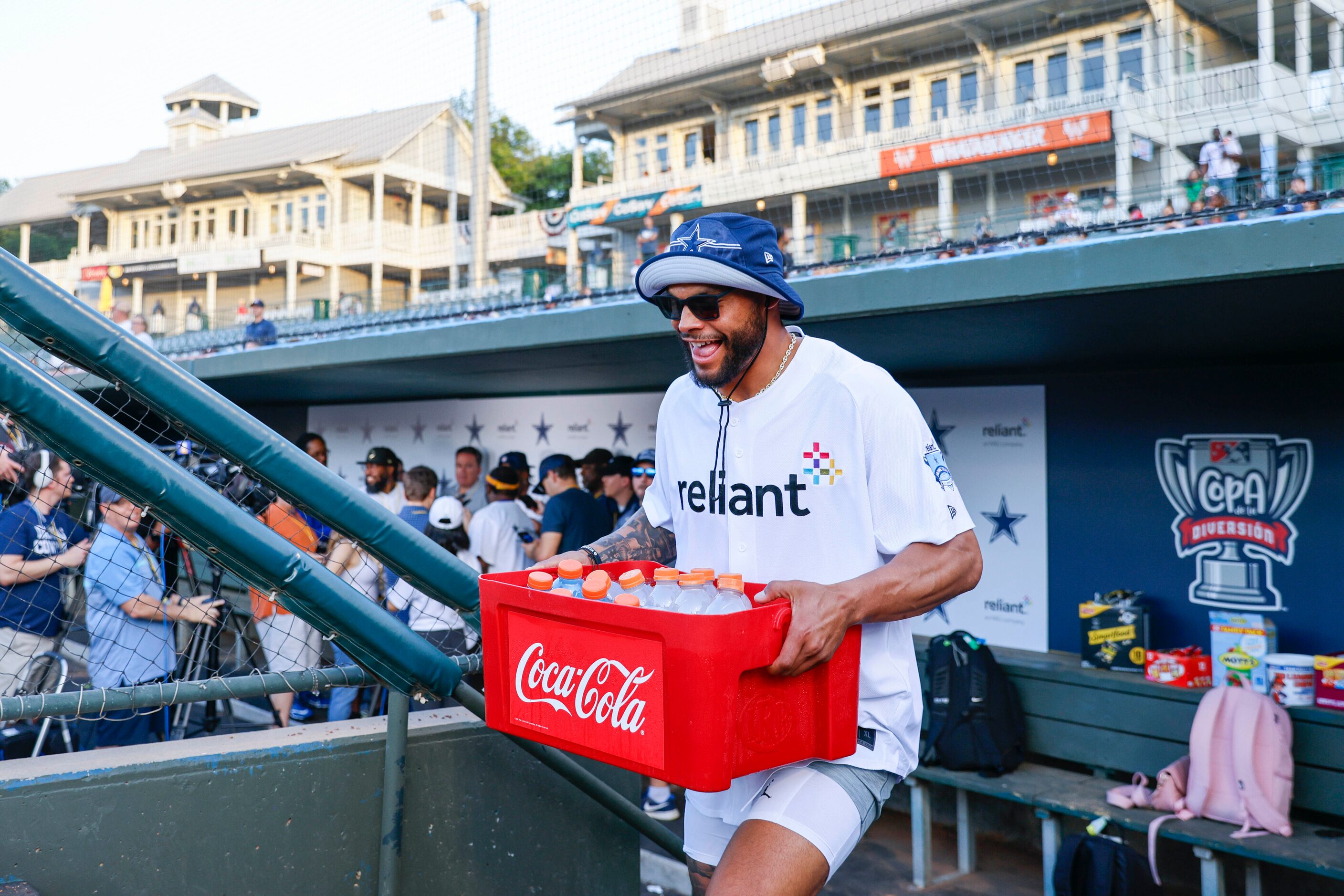 Dallas Cowboys QB Dak Prescott walks out of the dugout carrying a case full of drinks during...