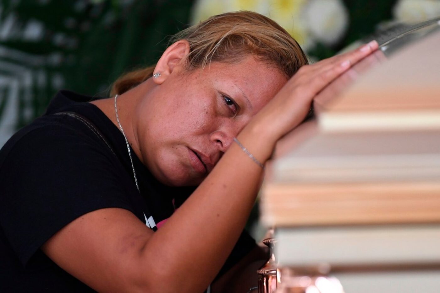 A woman mourns as she leans against the coffin of a victim of the attack at the Caballo...