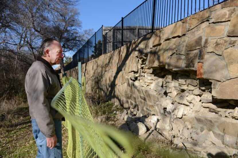 Duncan looks at the damage on the retention wall behind his house on Feb. 12, 2014 in...