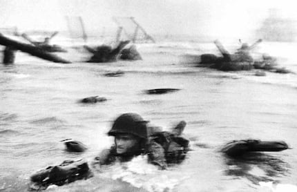 An American soldier wades through water under heavy artillery and machine-gun fire to reach...