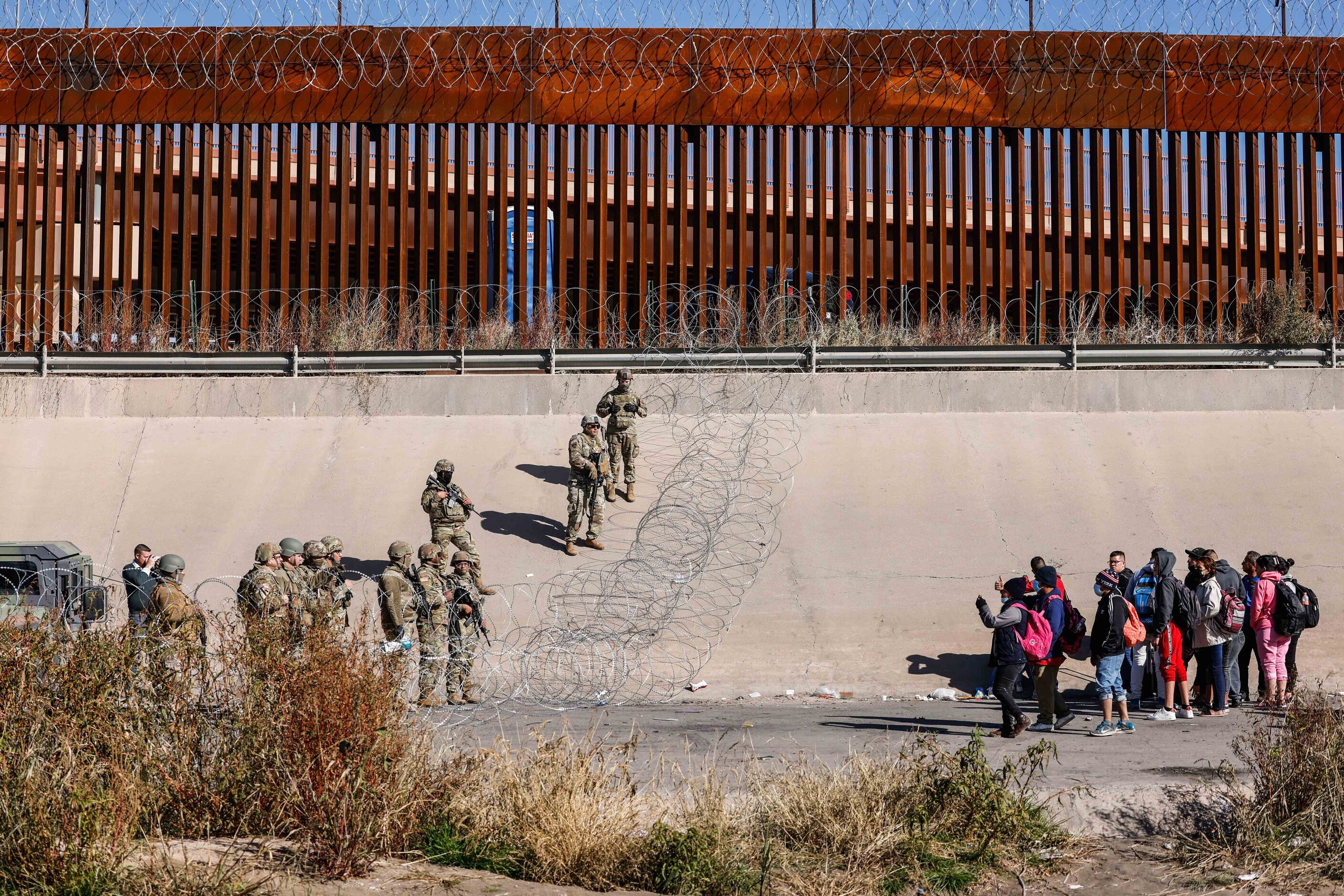 Migrants start to gather close to where the end of Texas National Guards are deployed at...