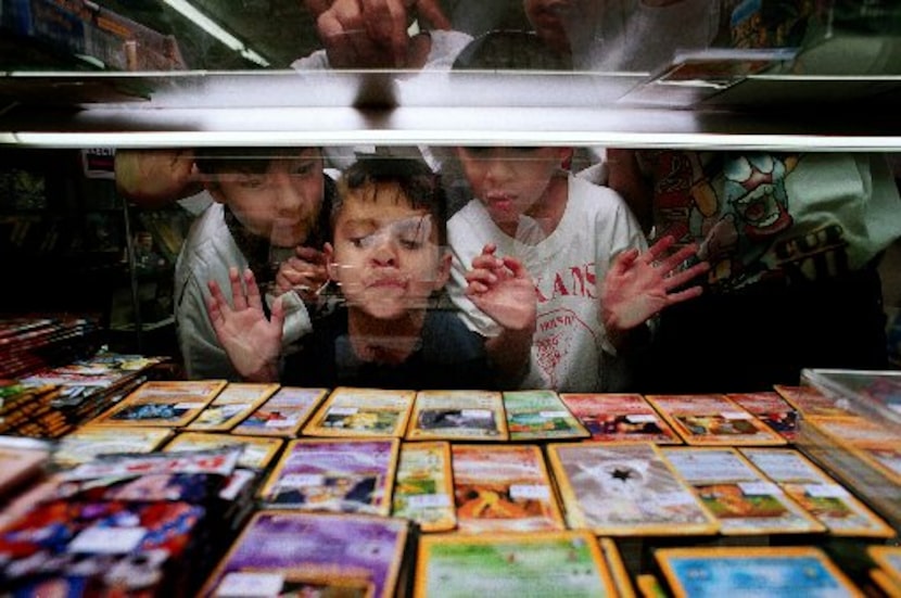 Larry Lopez, 11, John Armijo, 4, and Jaime Lopez, 10, look at rare Pokemon cards through a...