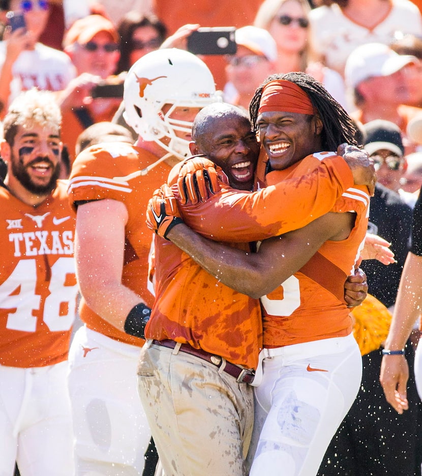 Texas head coach Charlie Strong hugs safety Adrian Colbert (26) after he is doused with a...