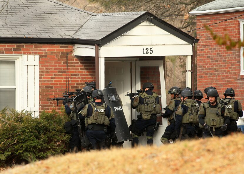 A police tactical team prepares to enter a home on Dade Avenue, in Ferguson, Mo., on...