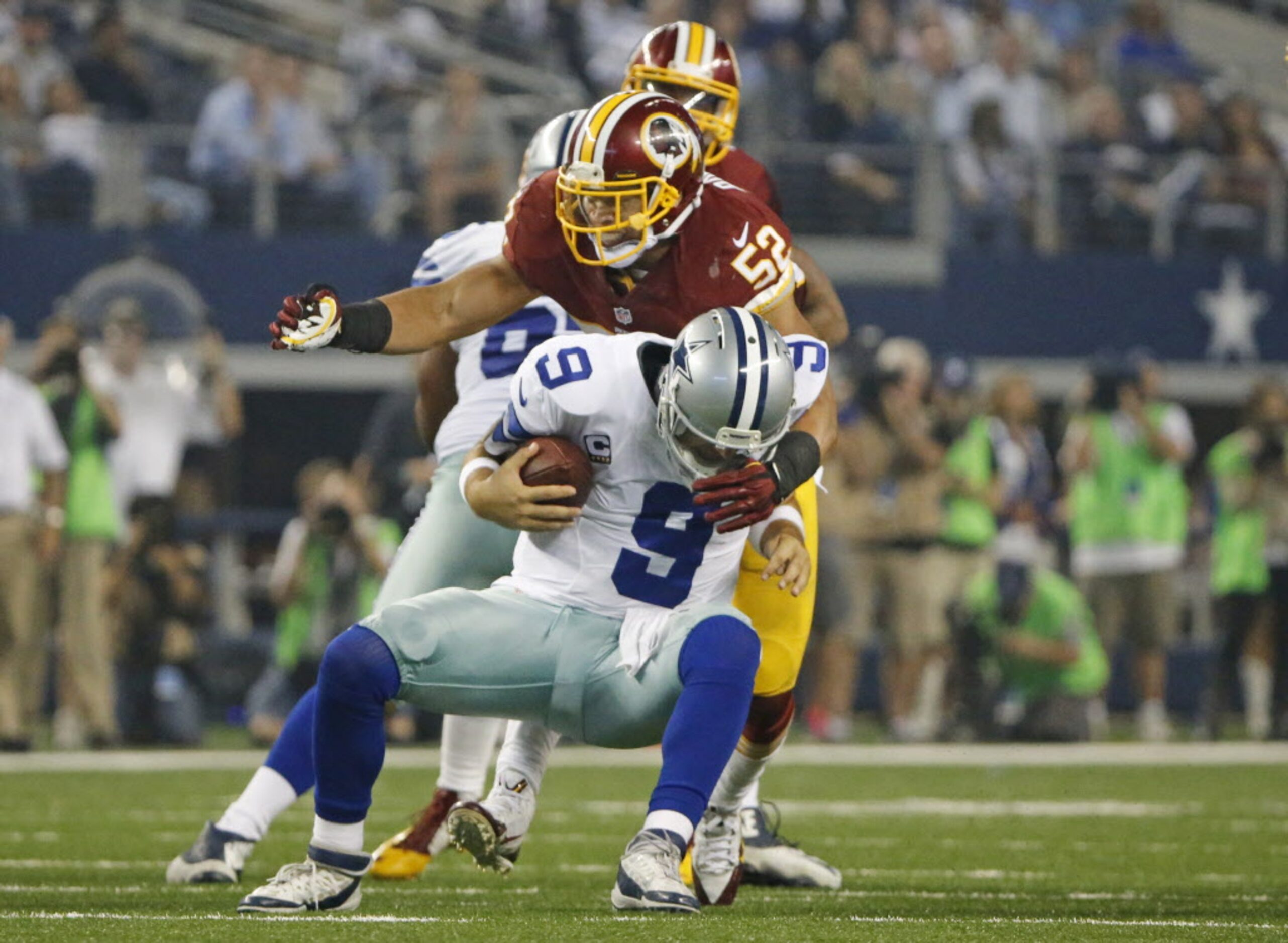 Dallas Cowboys quarterback Tony Romo (9) is crunched by Washington Redskins inside...