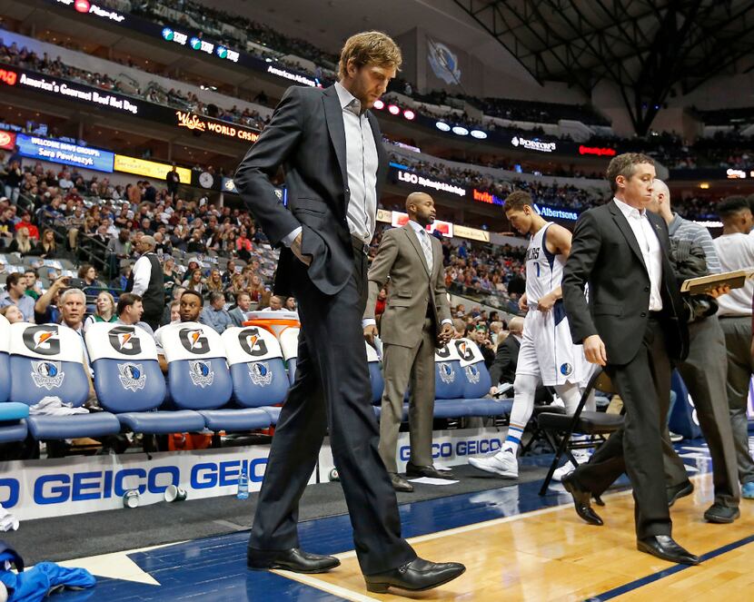 Dallas Mavericks forward Dirk Nowitzki in a suit walks on the court during a timeout in the...