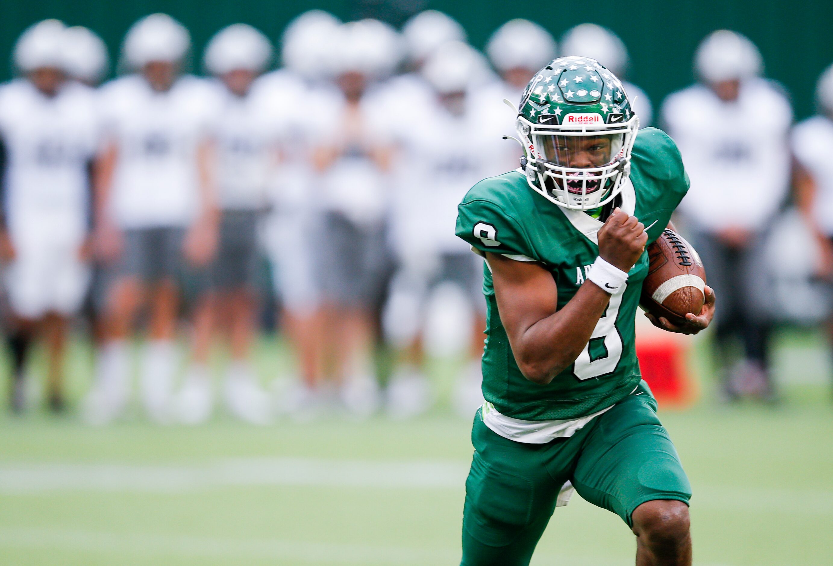 Arlington quarterback Kris Sims (8) carries the ball during the first half of a high school...