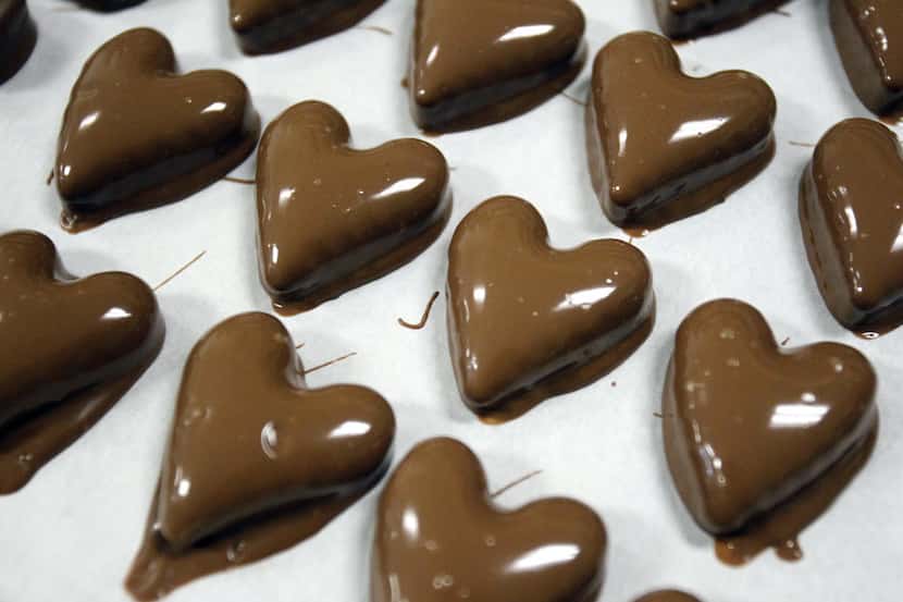 Chocolate covered caramel hearts are laid out after going through the enrober at Daisy's...