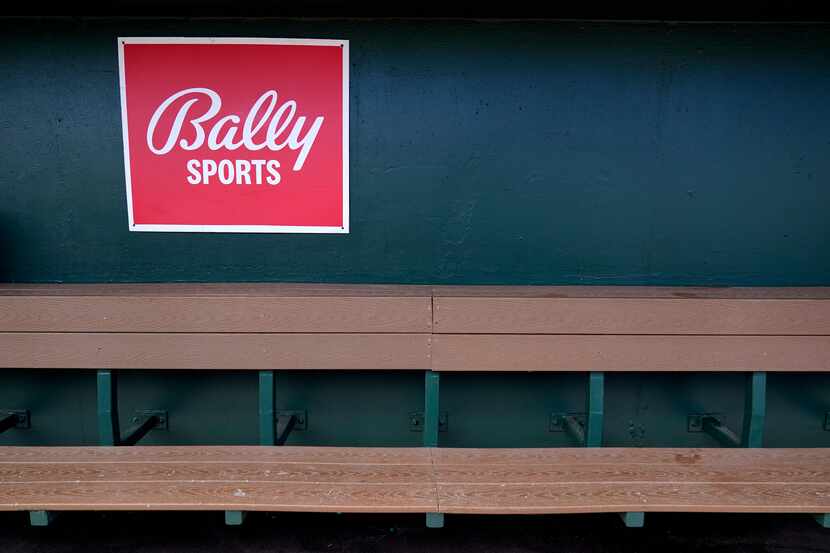 A Bally Sports sign hangs in an empty dugout before the start of a spring training baseball...