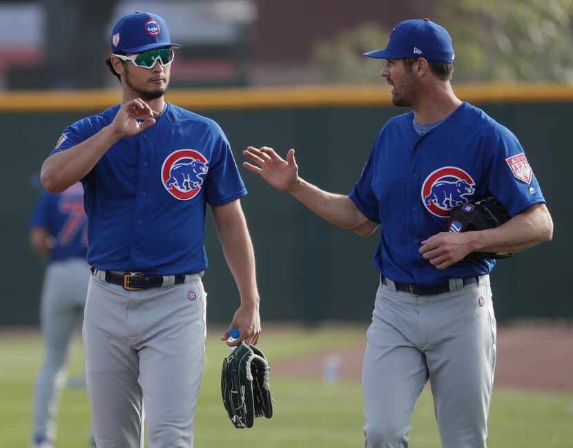 Chicago Cubs' Yu Darvish talks to Cole Hamels during a spring training baseball workout...