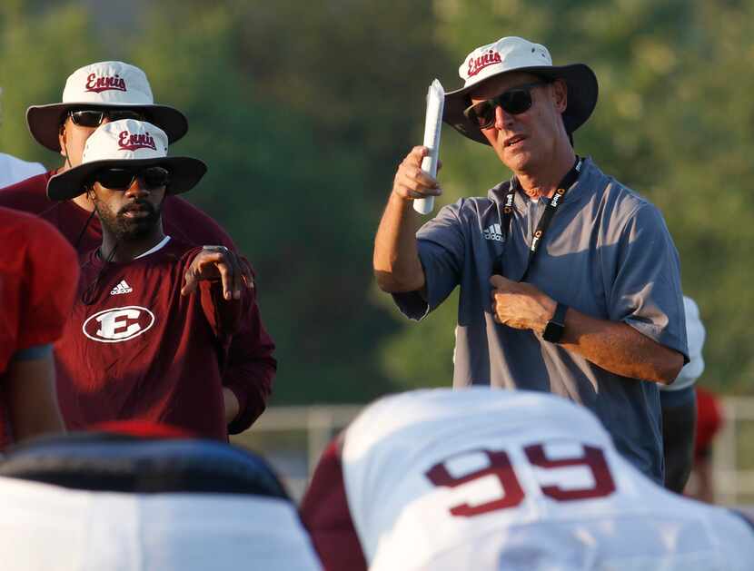 Ennis head football coach Sam Harrell makes a point as he confers with his assistants during...